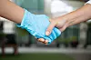 new normal hand shake between people following social distancing or personal distancing guideline by using clean new rubber glove to avoid direct contact while hand shaking with other people