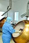 Person in Schutzkleidung vor Tank, GMP, Pharma, Produktion, Containment