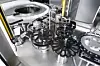 Übergabe der Vials an das Individualtransportsystem. Die Drehteller für den Transport der Vials sind filigran gebaut, um der Luftströhmung von oben, die entstehende Partikel wegführen soll, wenig Widerstand entgegenzusetzen.