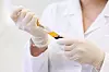 the uncertain doctor in medical gloves gathers in syringe plasma from test tube with the patient`s blood