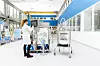 Laborantin arbeitet an Edelstahl-Produktionsanlage in hellem Reinraum