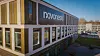 Bürogebäude mit Novoness-Logo an der Fassade und Parkplatz im Hintergrund