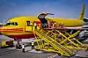 DHL-Frachtflugzeug wird von Bodenpersonal über gelbe Treppenanlage beladen