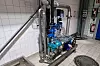 Blaue Pumpen- und Rohrleitungsanlage in einem gefliesten Technikraum.