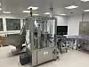 Edelstahl-Abfüllanlage in einer hellen Produktionshalle mit Förderbändern und Monitoren.
