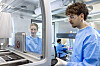 Zwei Mitarbeitende in blauen Kitteln arbeiten in einem modernen Labor des Translational Science Center.