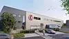Fiege-Logistikhalle mit Logo, Lieferwagen und Straße vor dem Gebäude.