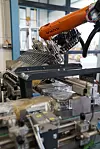 Orangefarbener KUKA-Roboter an einer automatisierten Produktionsanlage in einer Fabrikhalle.