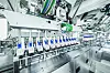 Automatisierte Maschinen und Fördertechnik in einer hellen Fabrikhalle.