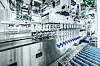 Automatisierte Maschinenanlage befördert blaue Behälter in einer Produktionshalle.