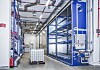 Industriehalle mit blauem Regalsystem, Rohrleitungen und einem IBC-Behälter auf einer Palette.