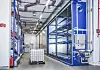 Industriehalle mit blauem Regalsystem, Rohrleitungen und einem IBC-Behälter auf einer Palette.