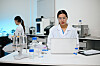 Zwei Wissenschaftlerinnen im Labor mit Laptop, Laborgeräten und Proben auf dem Tisch.